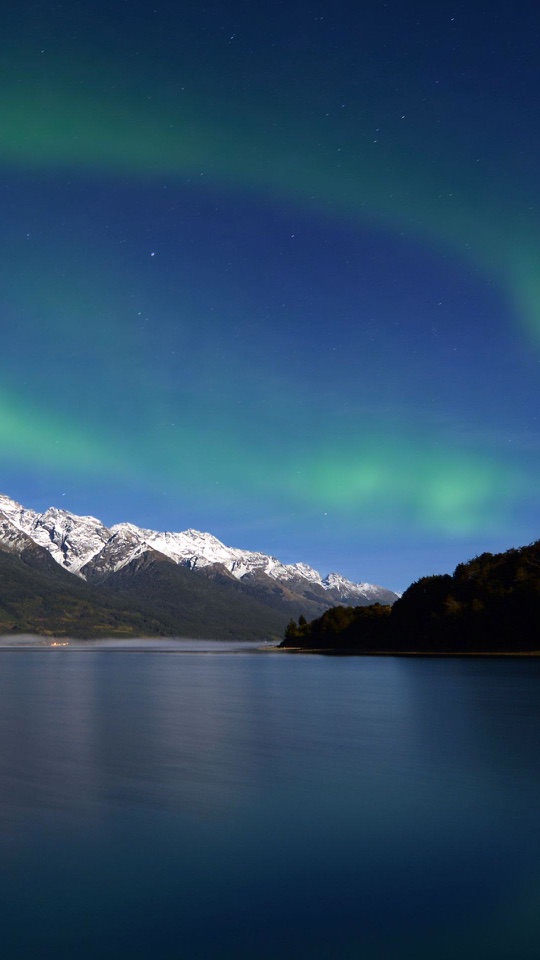 夜空に緑のオーロラが揺らめき、下に雪山と湖が広がります。