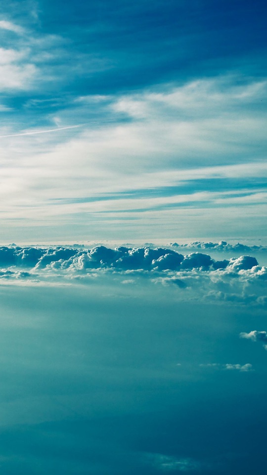 青空の下、水平線に沿って雲がたなびき、その下に穏やかな海が広がるミニマルな写真。