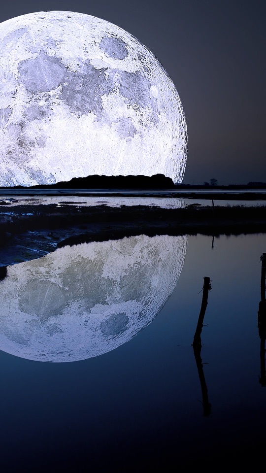 夜の湖の上に大きな満月が昇り水面に映っています。