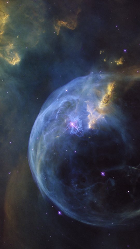 ハッブル宇宙望遠鏡の画像。青紫のガスの泡が、赤と橙の雲を背に浮かぶ。