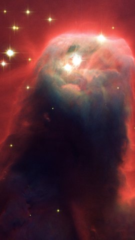 ハッブル宇宙望遠鏡の画像。赤い光を背に、暗いガスの円錐が下から立ち上がる。