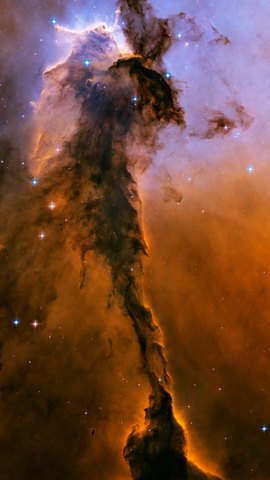ハッブル宇宙望遠鏡の画像。橙と褐色のガスの塔が、青緑の光の中に高くそびえる。
