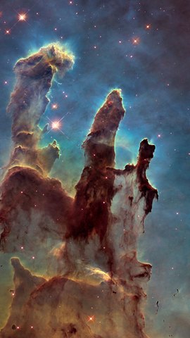 ハッブル宇宙望遠鏡の画像。青緑の光を背に、褐色のガスの柱が三本立ち上がる。