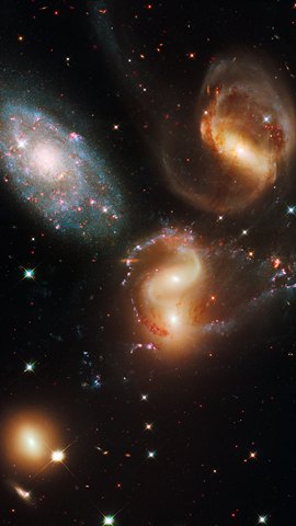 ハッブル宇宙望遠鏡の画像。黒い宇宙に、互いに近づいた複数の銀河が並ぶ。