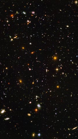 ハッブル宇宙望遠鏡の画像。真っ黒な宇宙に、色も形も異なる小さな銀河が無数に散らばる。