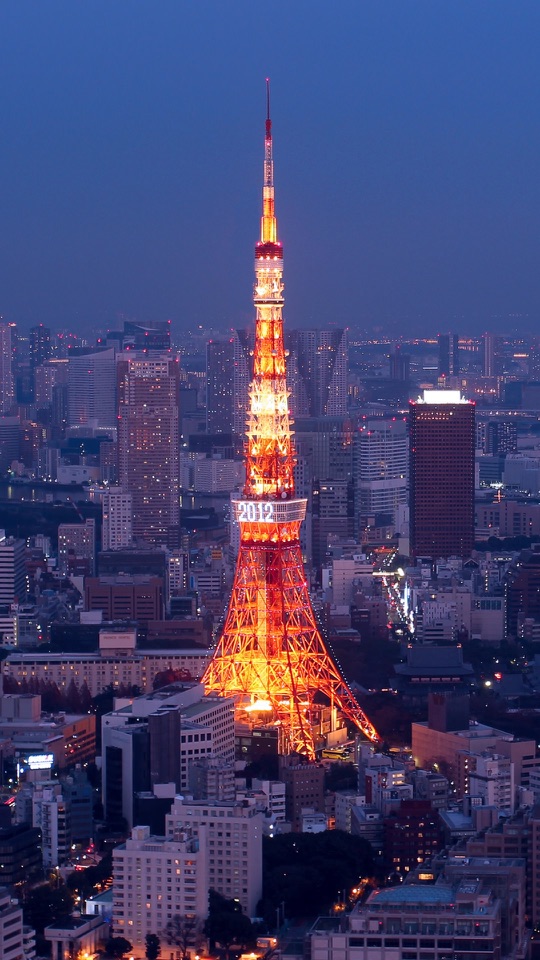 紺の夕空を背に、橙色に灯る大きな鉄塔が街並みの中にそびえます。