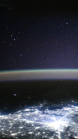 国際宇宙ステーションから見た夜のニューデリー。上に星空と大気の光の帯、下に白く輝く街明かり。