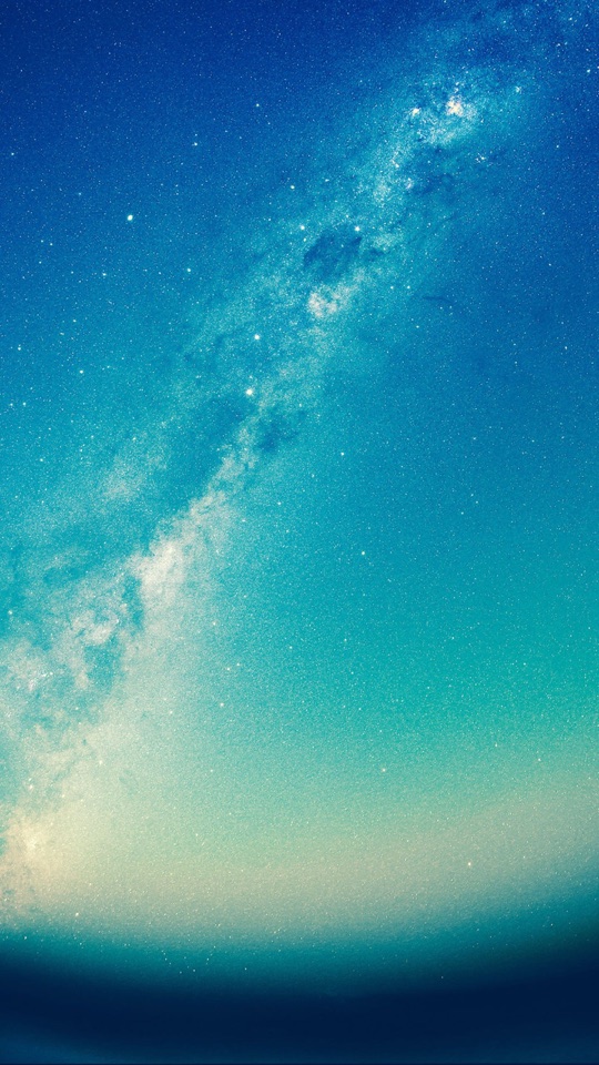 湾曲した地平線の上に、青緑に染まる空と天の川、無数の星が広がる写真。