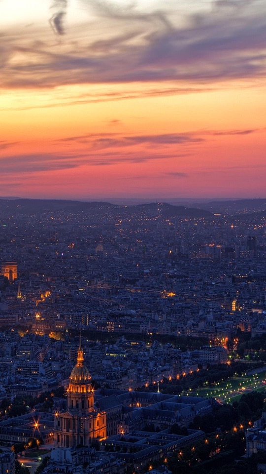 オレンジと紫に染まる夕空の下、金色のドームが灯る街並みを高所から見渡します。