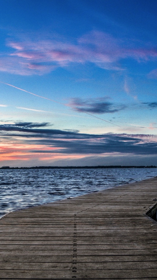 夕焼けに染まる空と海を背に、木の桟橋が沖へと伸びていく風景写真。