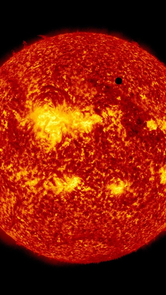 赤く燃える太陽の球面に小さな黒点が写っています。