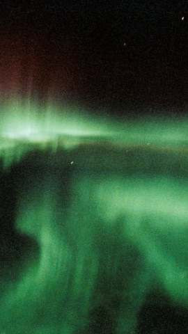 スペースシャトルから撮影したオーロラ。黒い宇宙を背に、緑のカーテンが画面いっぱいに揺れる。
